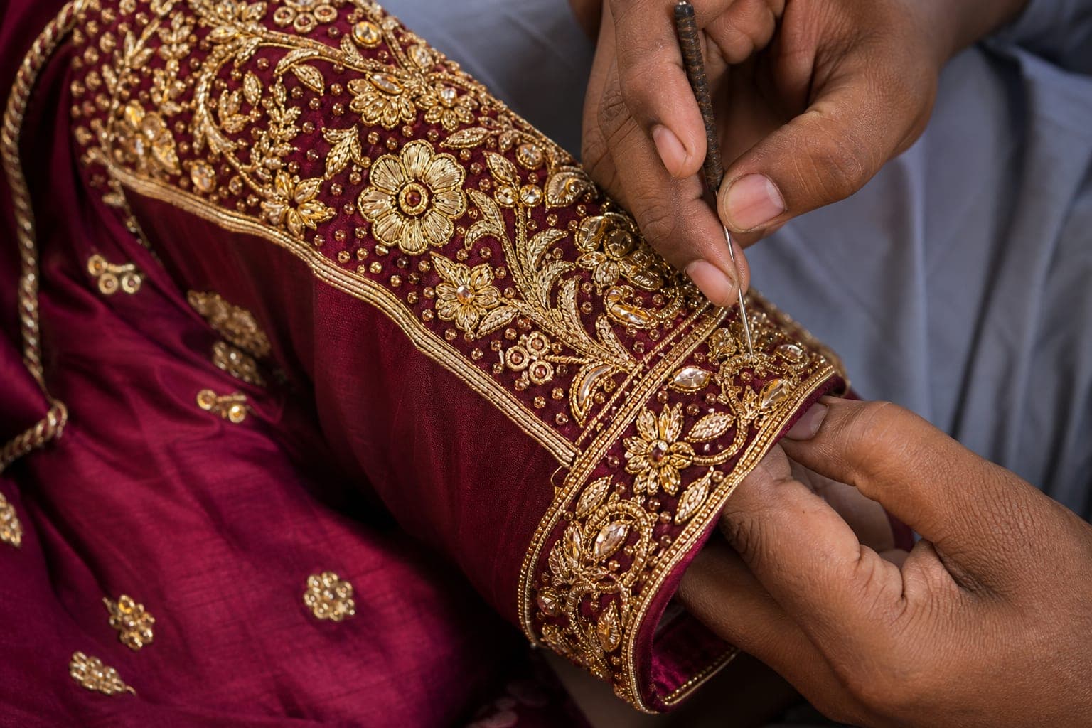 Indian artisan stitching aari work on lehenga sleeve